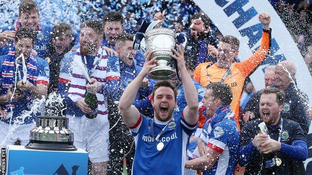 Linfield captain Jamie Mulgrew lifts the Gibson Cup after the Premiership title was secured