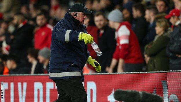 A steward at the stadium can be seen removing the bottle