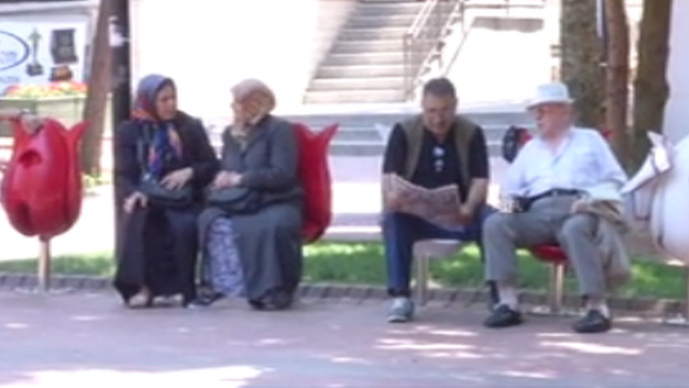 Women sitting on the individual seats, with two men sitting next to them