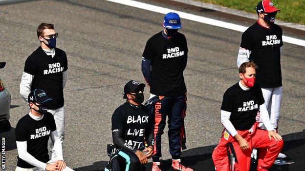 Lewis Hamilton kneels on the tarmac