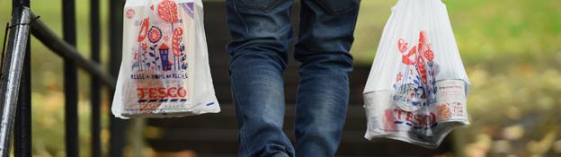 shopper holds a tesco carrier bag in each hand