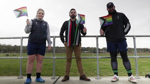 Amy Cokayne, Nicholas Hackett-Peacock and Will Collier wave rainbow flags