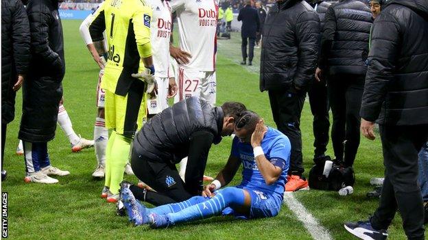 Dimitri Payet is treated after being hit by a thrown bottle