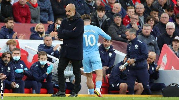 Pep Guardiola (centre) and Manchester City members of staff on the bench at Anfield