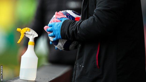 A ball boy or girl cleans a football with sanitiser