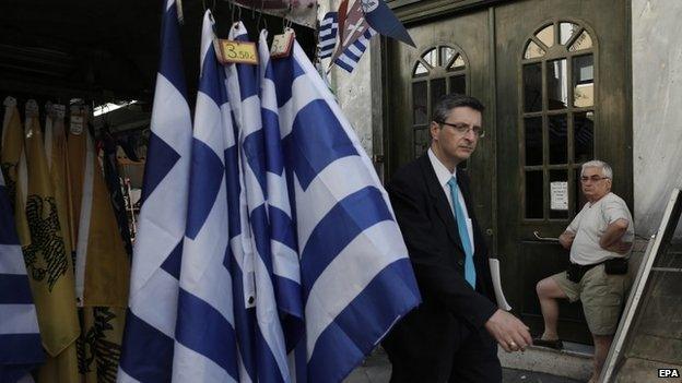 Man walks past stall selling Greek flags