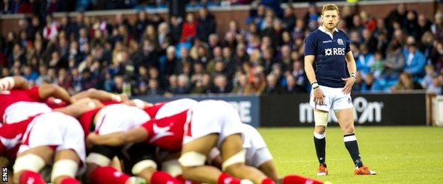 Tonga players in a scrum watched by Scotland's Finn Russell