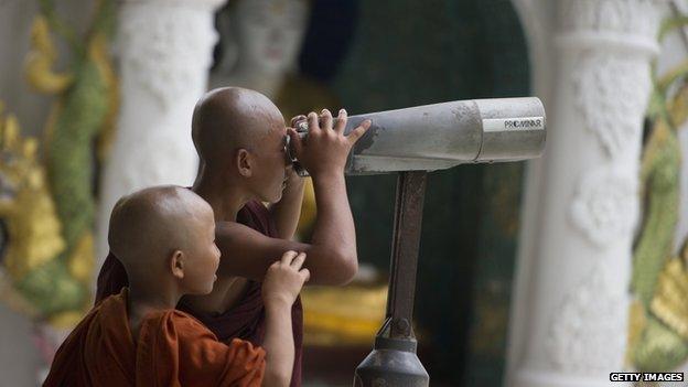 Buddhist novice monks look through a telescope in Yangon