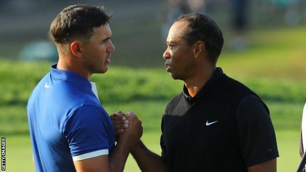 Brooks Koepka greets Tiger Woods after their contrasting rounds