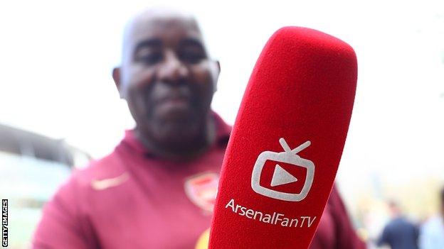 AFTV member Robbie Lyle poses with a microphone outside the Emirates Stadium