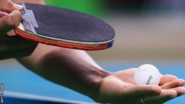 A table tennis ball and paddle