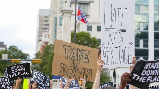 People hold signs during a protest asking for the removal of the confederate battle flag that flies at the South Carolina State House in Columbia