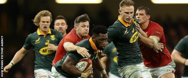 Steff Evans of Wales tackles Siyo Kolisi during the rugby Test match in Cardiff