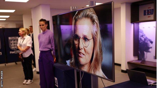 Sarina Wiegman speaks to the 1972 players on a video screen