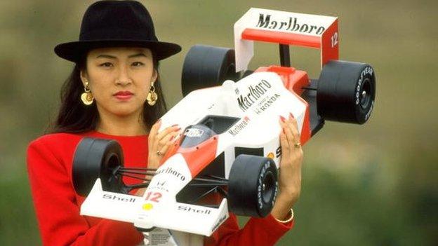 a model holds a model of a mclaren honda in 1988