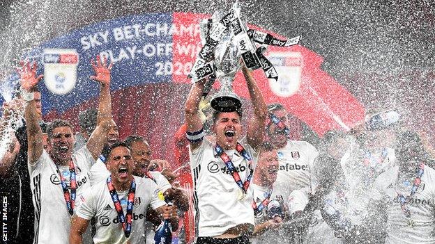 Fulham's Tom Cairney lifts the trophy as the team celebrates