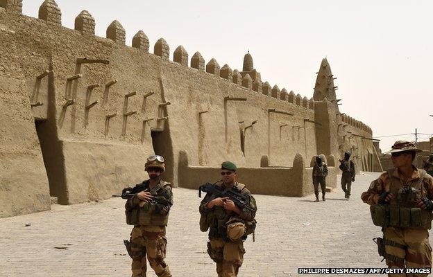 French soldiers of the 93rd Mountain Artillery Regiment and soldiers of the Malian Armed Forces patrol next to the Djingareyber Mosque on June 6, 2015 in Timbuktu