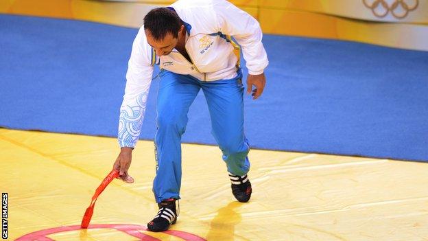 Greco-Roman wrestler Ara Abrahamian of Sweden places his bronze medal at the center of the competition mat in protest of the result in the men's Greco-Roman 84kg wrestling category during the 2008 Beijing Olympic Games