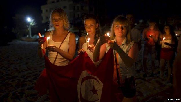 People hold candles as they walk to the beach of the Imperial Marhaba Hotel