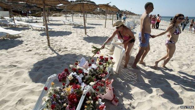 A tourist places flowers at the beachside of the Imperiale Marhaba hotel, which was attacked by a gunman in Sousse