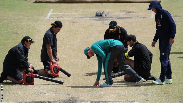 Groundstaff attempt to dry the pitch at Perth as Steve Smith and Joe Root inspect it