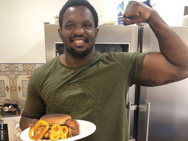 Dillian Whyte poses with the chicken burger he made for the charity chicken burger challenge against Eddie Hearn