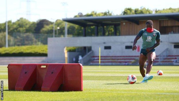 Southampton forward Michael Obafemi wears a cover over his mouth as he takes part in training