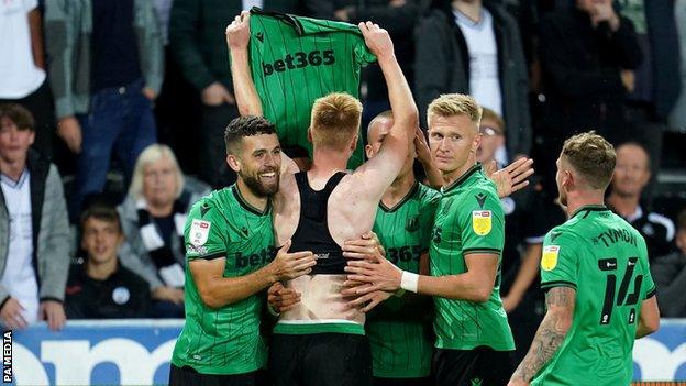 Sam Clucas yn codi ei grys o flaen cefnogwyr Abertawe