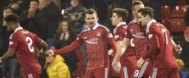 Jonny Hayes take the plaudits from his Dons team-mates after notching the early opener