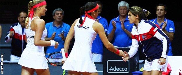 French Fed Cup team captain Amelie Mauresmo (R) encourages Caroline Garcia (C) and Kristina Mladenovic