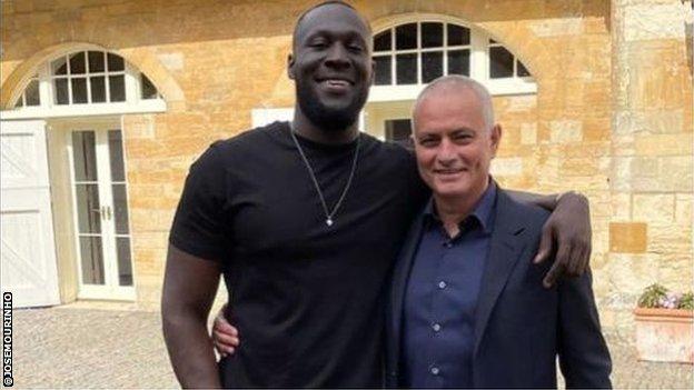 Stormzy and Jose Mourinho embrace.