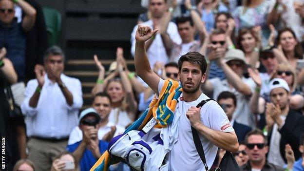 Cameron Norrie waves to the Wimbledon crowd after losing to Roger Federer