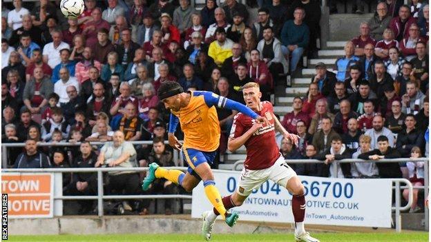 Mansfield Town defender James Perch (14) heads the ball under pressure from Northampton Town forward Mitch Pinnock