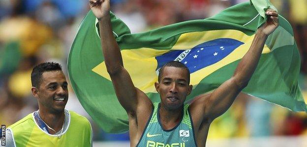 Brazil's Ricardo Costa de Oliveira celebrates with the Brazilian flag after winning gold in the T11 long jump