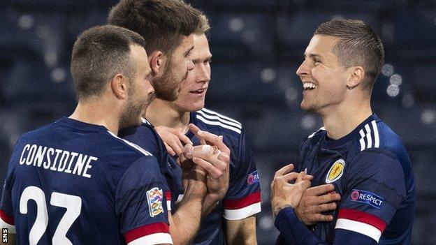 Andrew Considine, Declan Gallagher and Scott McTominay congratulate Lyndon Dykes