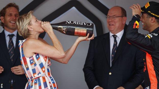 Australian Formula One driver Daniel Ricciardo of Aston Martin Red Bull Racing (R) celebrates on the podium with Prince Albert II of Monaco (C) with his wife Princess Charlene (L)