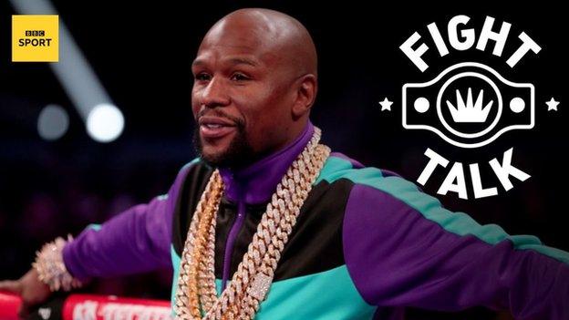 Former world champion Floyd Mayweather leans against the rope while wearing a gold chain an tracksuit top