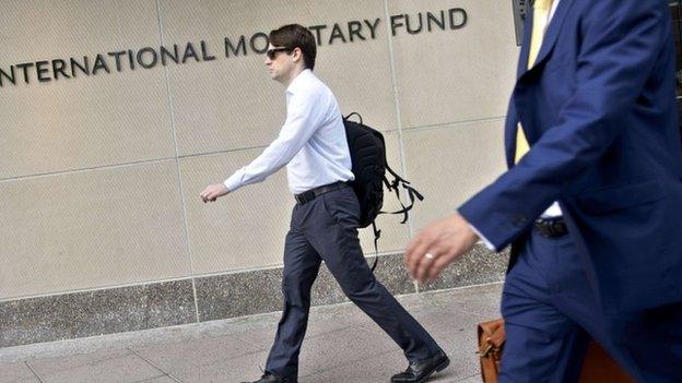 People walk past the headquarters of the International Monetary Fund on 30 June 2015 in Washington, DC.