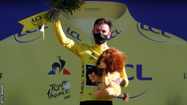 Adam Yates celebrates taking the yellow jersey on the podium