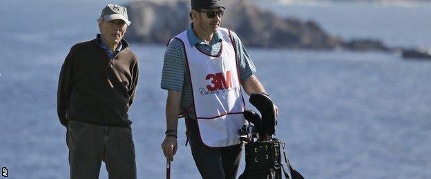 Three-time Open champion Nick Faldo, right, caddying for actor and director Clint Eastwood