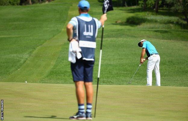 Francesco Molinari of Italy hits a putt at right angles to the hole on the 12th as caddy John McLaren tends the pin during the final round of the Alfred Dunhill Championship at Leopard Creek Country Golf Club on December 14, 2014 in Malelane, South Africa