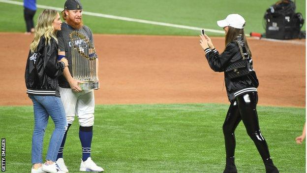 Justin Turner and his wife pose with the trophy while someone else takes a photo