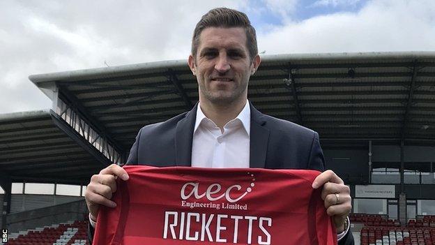 Sam Ricketts holds a Wrexham shirt with his name on it