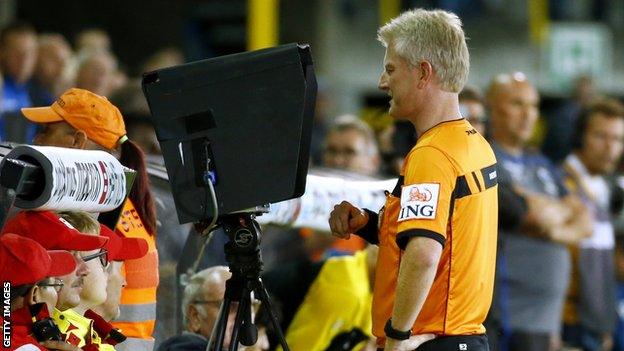 A referee examines replays at the Jupiler Pro League match between Club Brugge and Lokeren