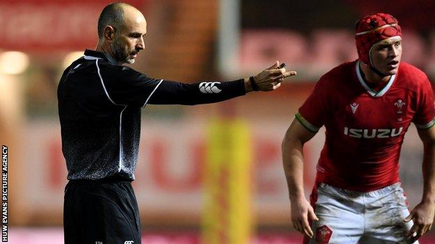 French referee Romain Poite with Wales flanker James Botham watching on