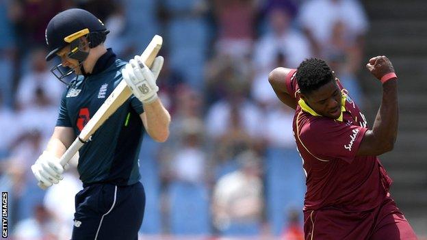 England captain Eoin Morgan (left) looks dejected as he walks off after being dismissed by Oshane Thomas (right) who swings his arm in celebration