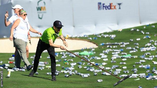 Beer cans being swept off the 16th green at TPC Scottsdale