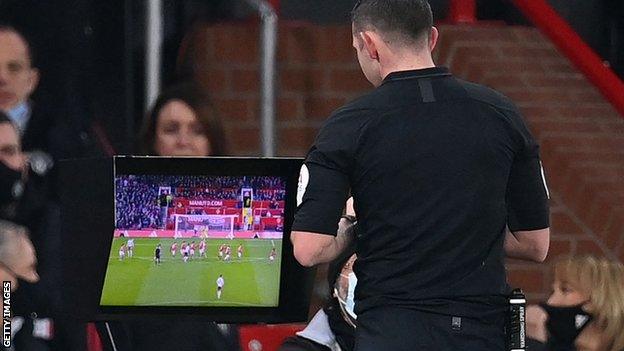 Michael Oliver checks the pitchside monitor at Old Trafford