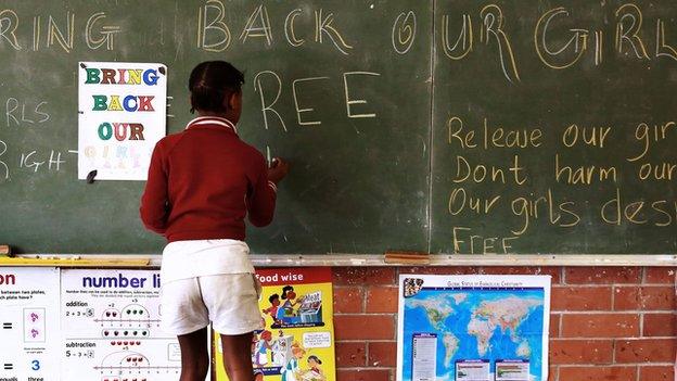 A South African girl, shown writing on a chalkboard