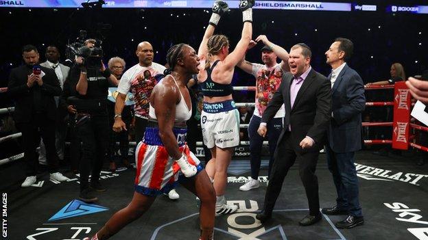 Claressa Shields celebrates with Savannah Marshall in the background